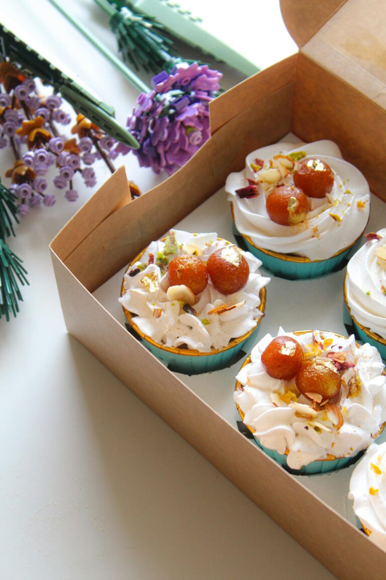 Gourmet Gulab Jamun cupcakes in a box with whipped cream and decorations.